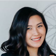 Asian American woman with long dark brown hair wearing a pink blazer and smiling